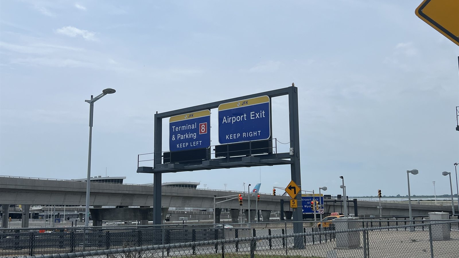 JFK roadway sign: Terminal 8 and parking keep left, airport exit keeps right