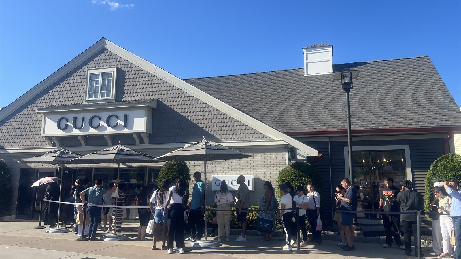 Queue behind rope barriers outside the Gucci store at Woodbury Common