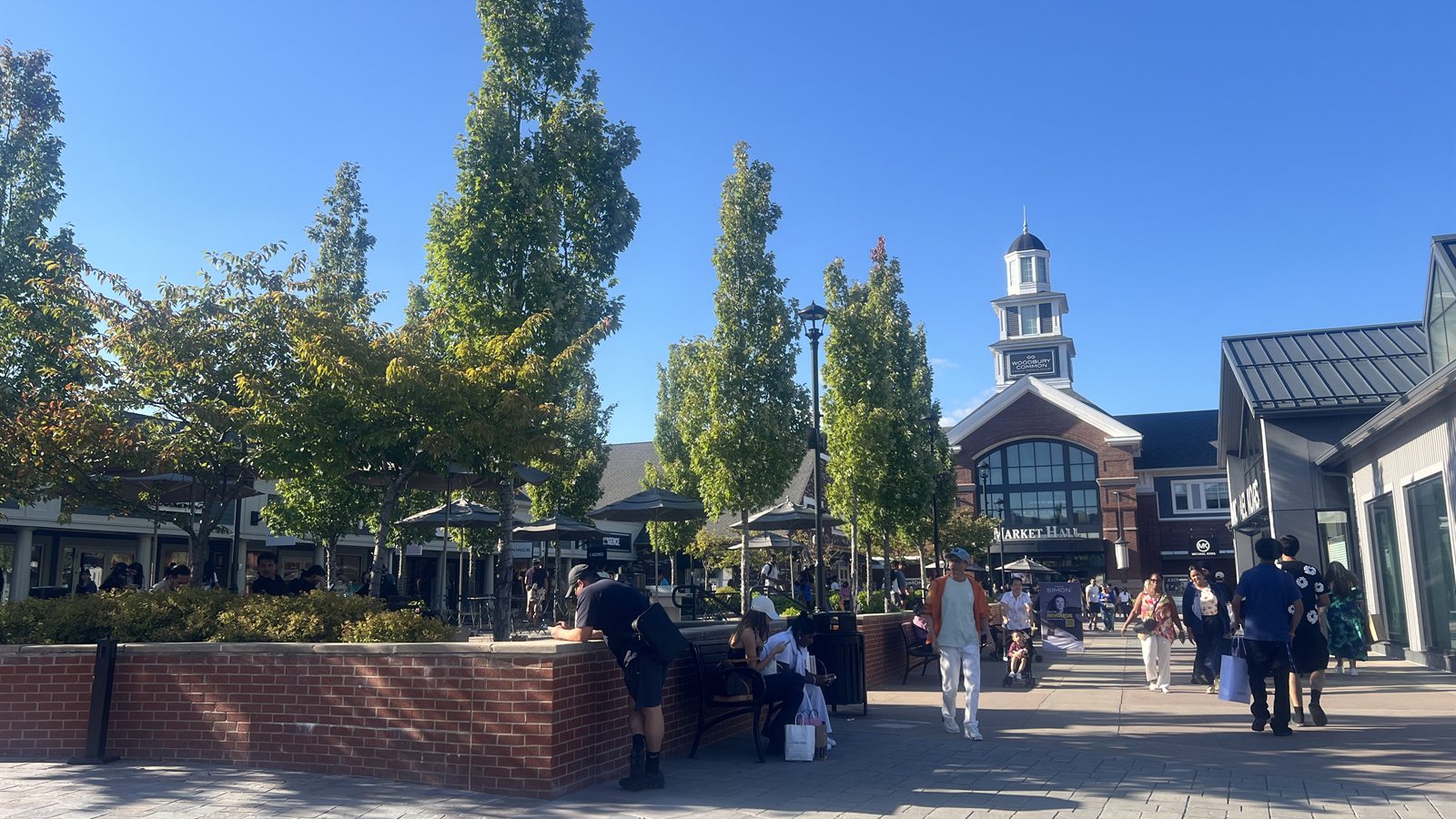 Market Hall and the white tower at Woodbury Common Premium Outlets, with the tree-lined pedestrian street in front
