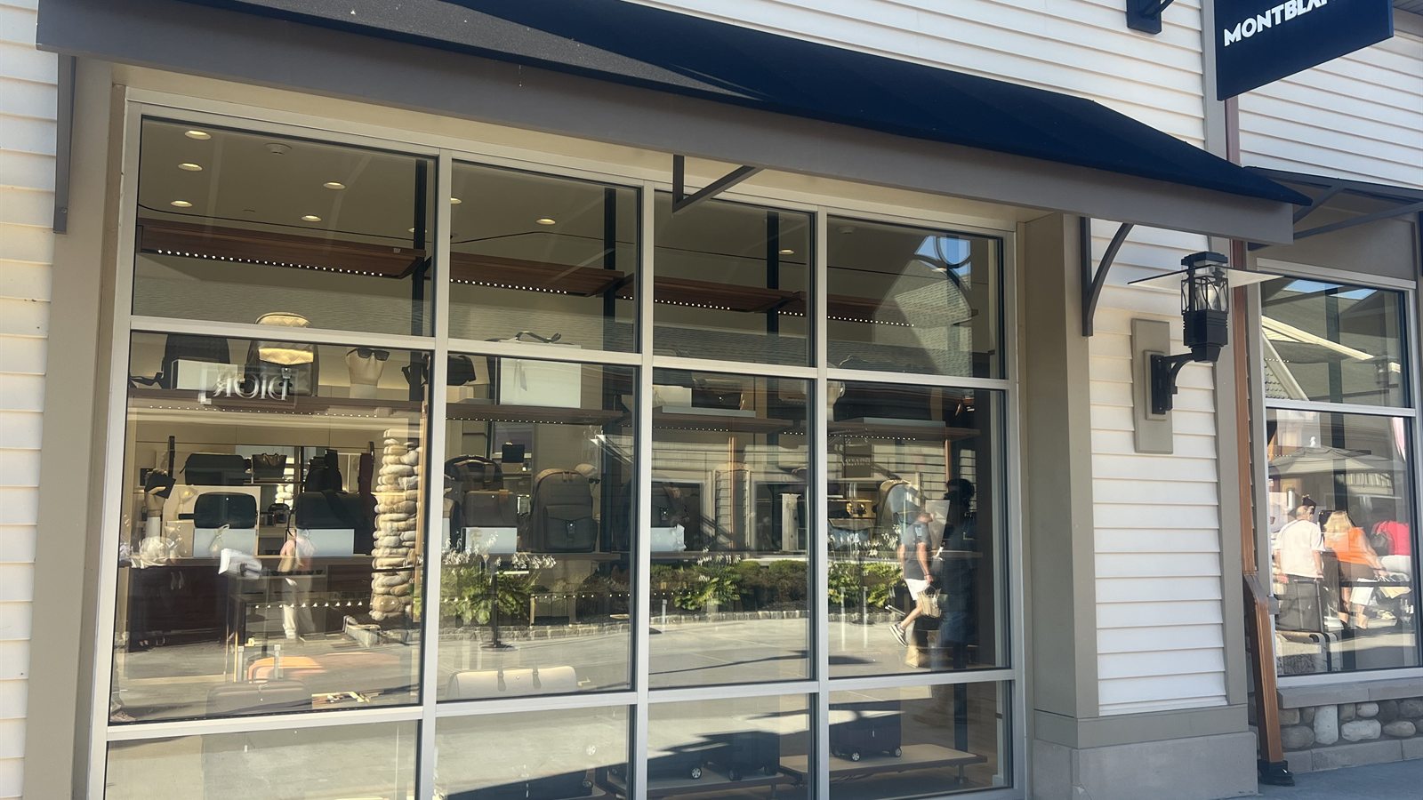 The Montblanc window at Woodbury Common with leather goods on display and the Dior sign reflected in the glass